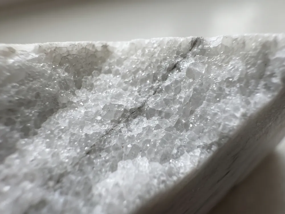 Borde partido de un mármol blanco visto de muy cerca: cristales de calcita encajados como un mosaico