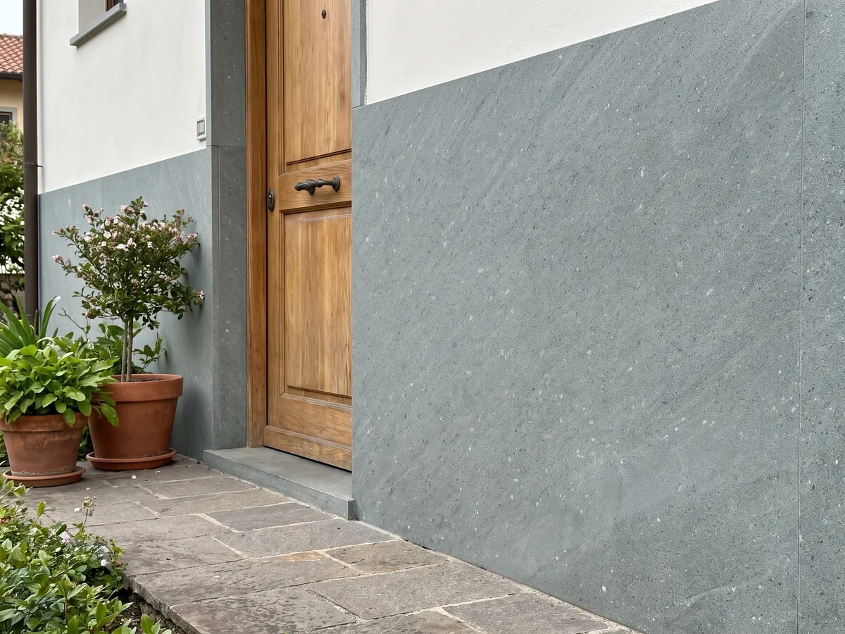 Fachada de casa revestida con Basalto Basaltite junto a una puerta de madera: gris verdoso de grano fino muy uniforme con puntitos blancos aislados
