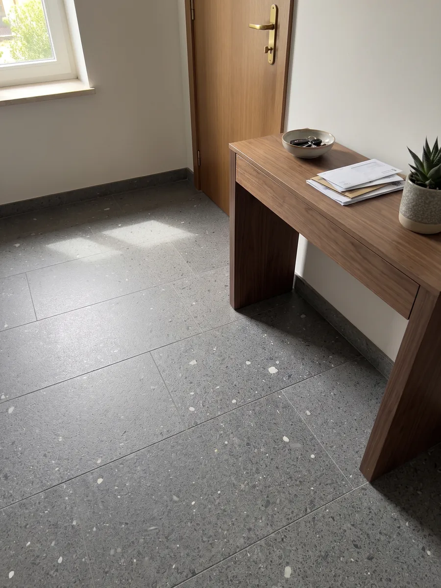 Piso de recibidor en placas grandes de Basalto Lavagrigia con luz natural: gris violáceo granulado tipo sal y pimienta con inclusiones blancas sueltas