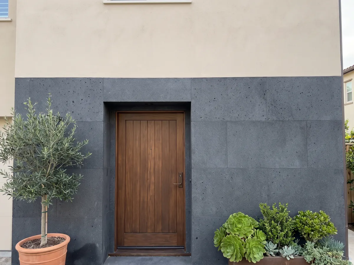 Fachada de casa revestida con Basalto Pietra Lavica junto a una puerta de madera: gris casi negro, homogéneo y de grano muy fino