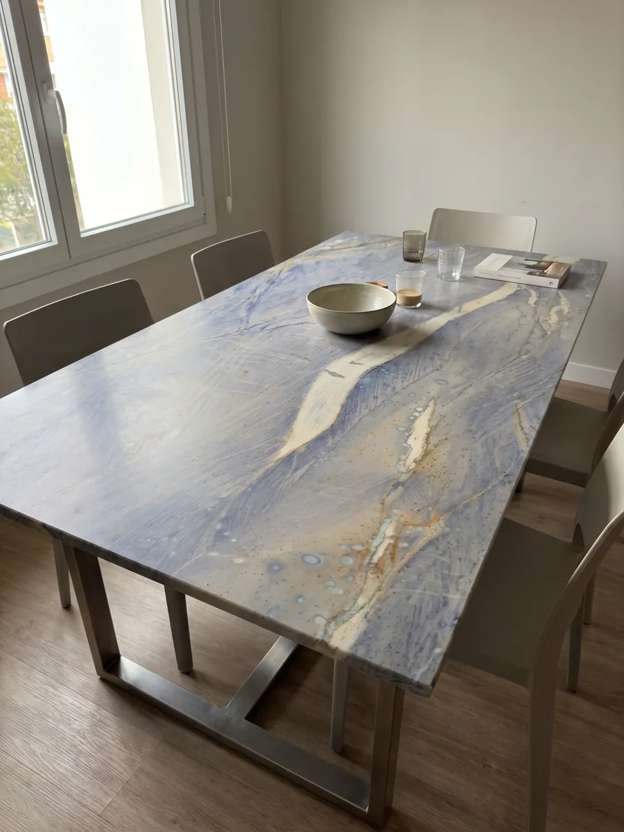 Mesa de comedor con cubierta de Cuarcita Azul Macaubas sobre base de acero: fondo azul lavanda con una gran franja crema en diagonal y toques ocre