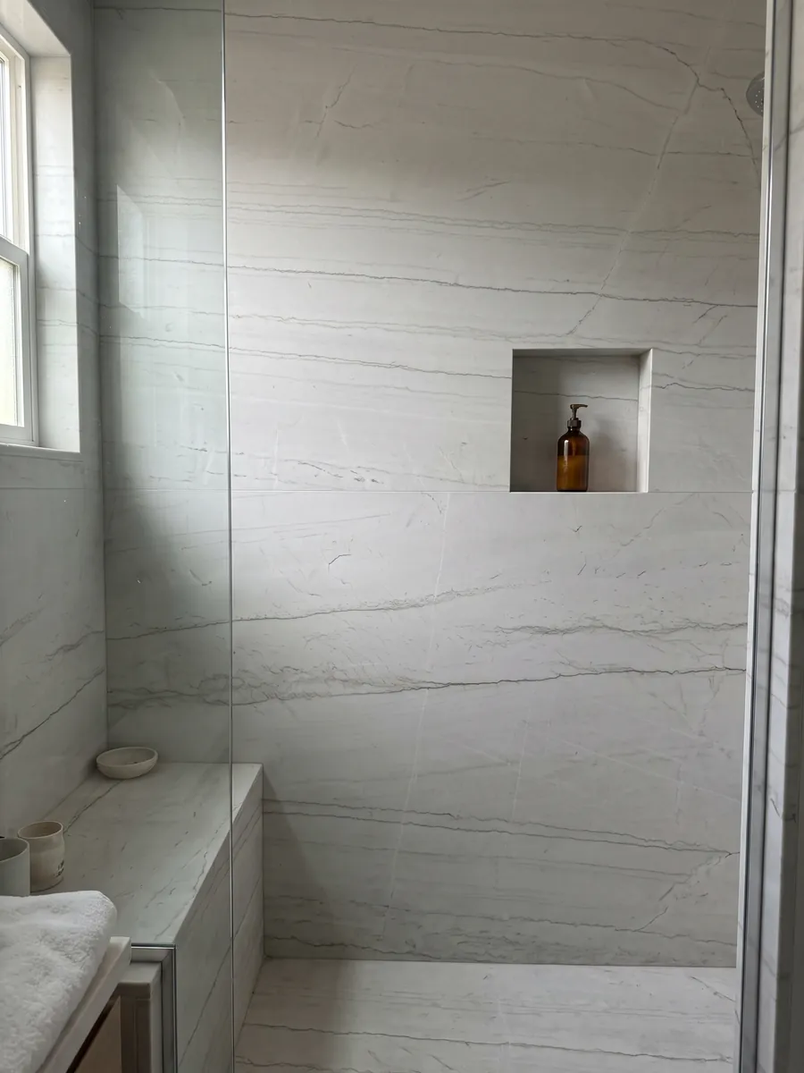 Ducha revestida con placas enteras de cuarcita blanca Mont Blanc con nicho empotrado: blanco casi limpio con dos o tres líneas grises muy finas