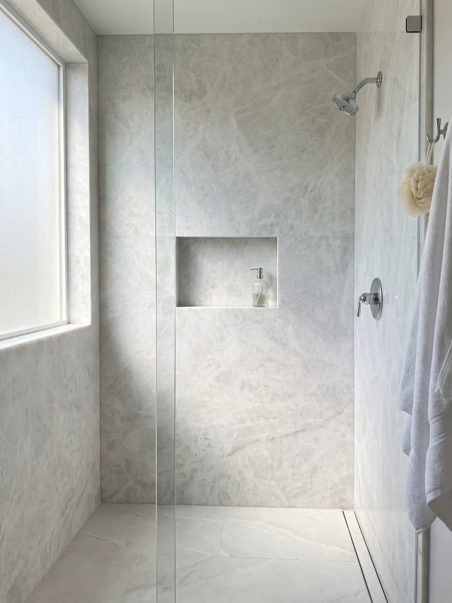 Ducha revestida con placas enteras de cuarcita gris Cristallo con nicho empotrado: blanco grisáceo casi uniforme con aspecto cristalino suave