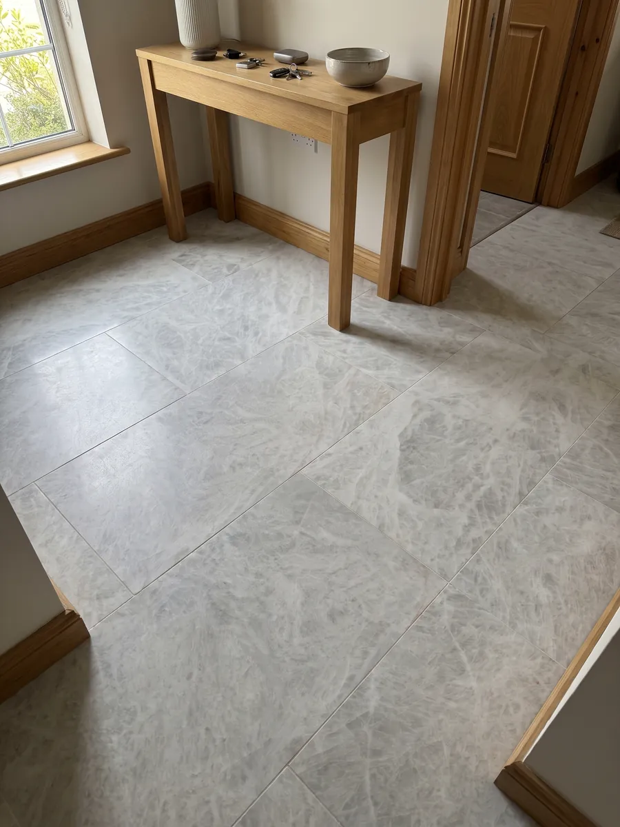 Piso de recibidor en placas grandes de cuarcita gris Cristallo con luz natural: blanco grisáceo casi uniforme con aspecto cristalino suave