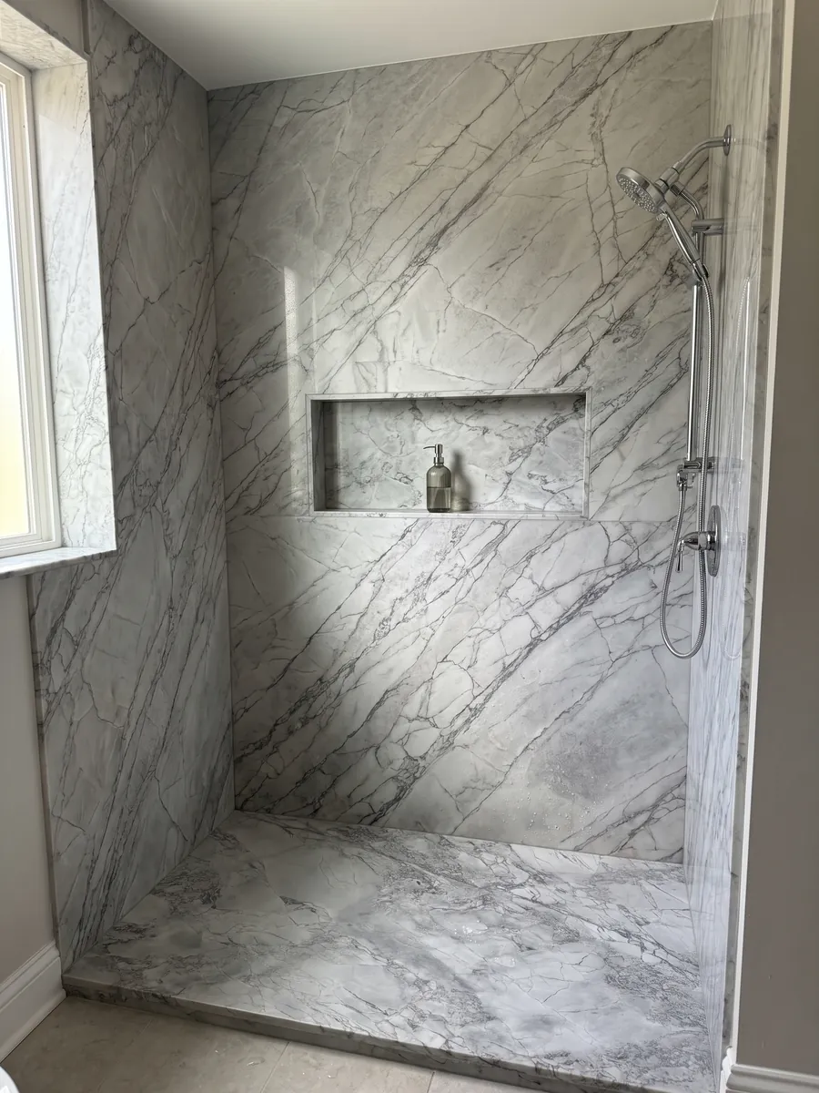 Ducha revestida con placas enteras de cuarcita gris Super White con nicho empotrado: gris claro con red de vetas grises algo más oscuras