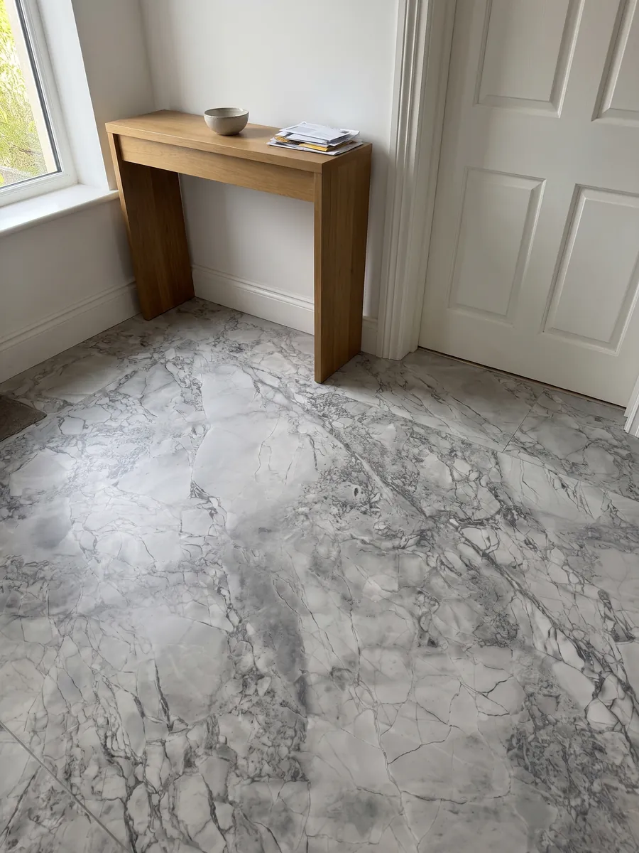 Piso de recibidor en placas grandes de cuarcita gris Super White con luz natural: gris claro con red de vetas grises algo más oscuras
