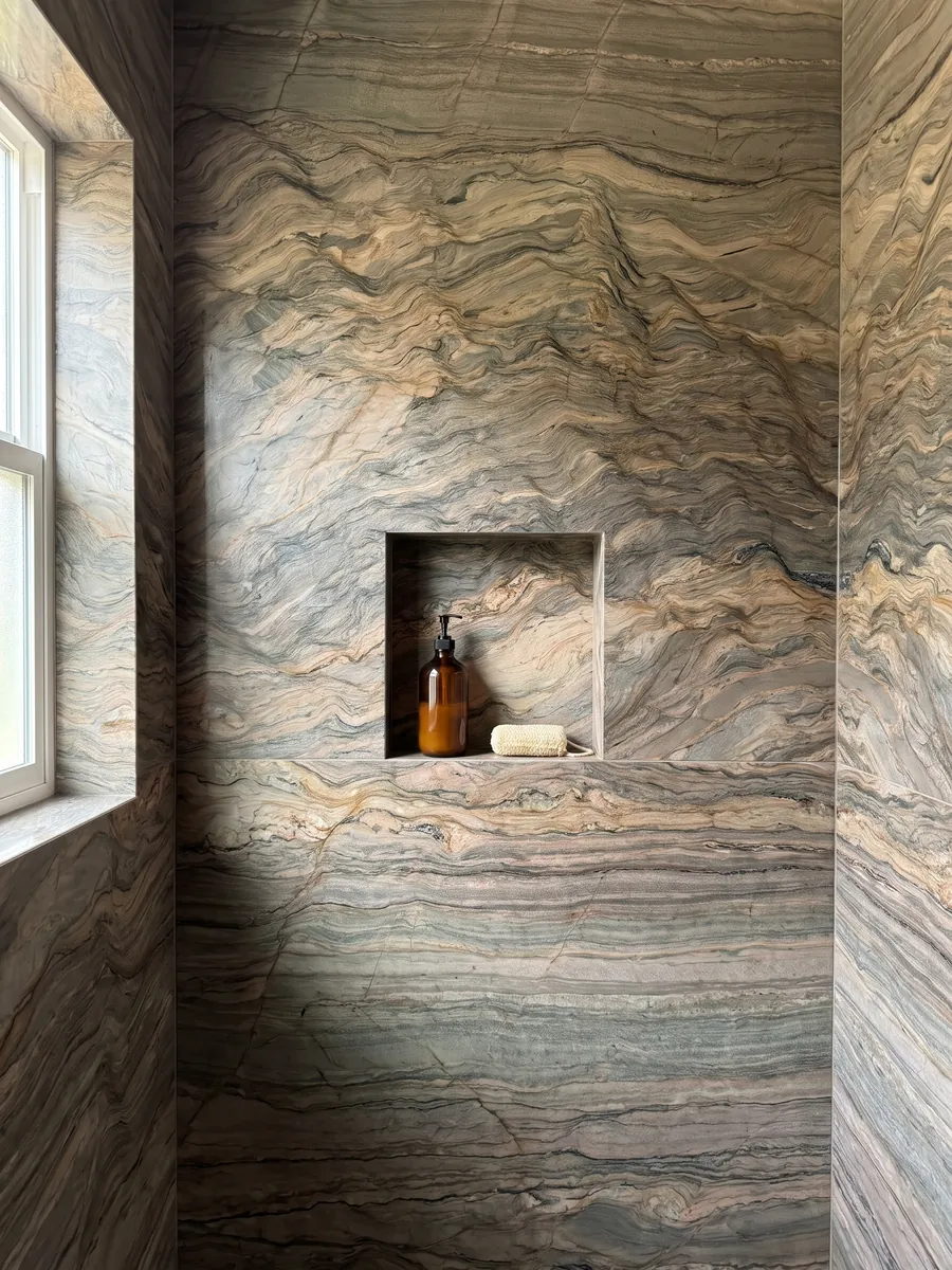 Ducha revestida con placas enteras de cuarcita marrón Fusion con nicho empotrado: ondas horizontales en ocre y gris verdoso, como capas de tierra