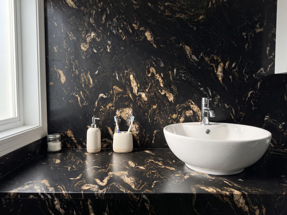 Cubierta de lavabo y pared de baño en cuarcita negra Titanium con lavamanos blanco y grifería cromada: negro con inclusiones doradas y beige en forma de llamas