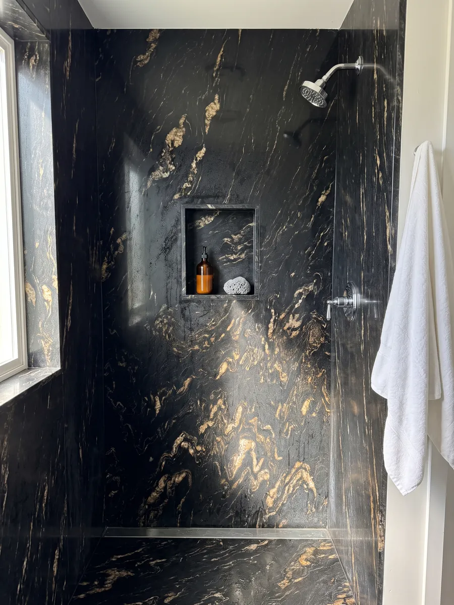 Ducha revestida con placas enteras de cuarcita negra Titanium con nicho empotrado: negro con inclusiones doradas y beige en forma de llamas