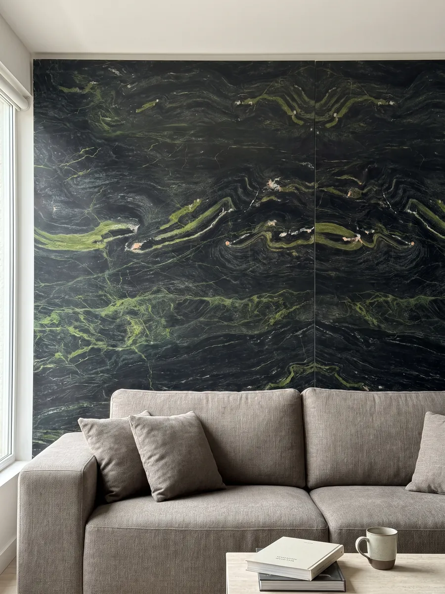Pared de sala revestida con placas de cuarcita negra Vancouver abiertas en libro detrás de un sofá: negro verdoso con ondas verde lima horizontales