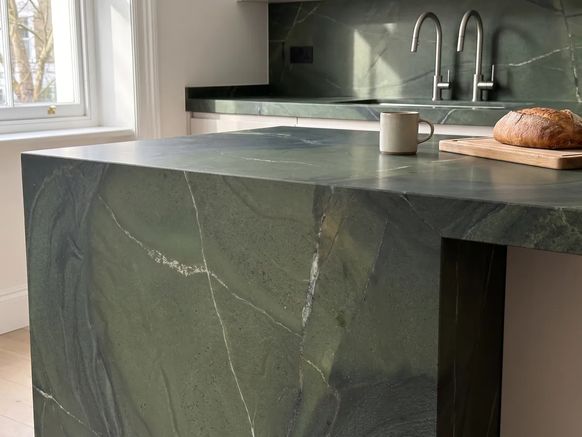 Isla de cocina con cubierta de cuarcita verde Avocatus y canto recto en una cocina con luz natural: verde profundo por zonas, cruzado por unas pocas líneas blancas finas