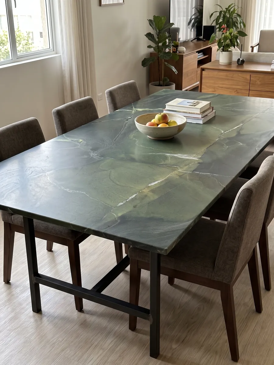 Mesa de comedor con cubierta de cuarcita verde Avocatus sobre base de acero: verde profundo por zonas, cruzado por unas pocas líneas blancas finas