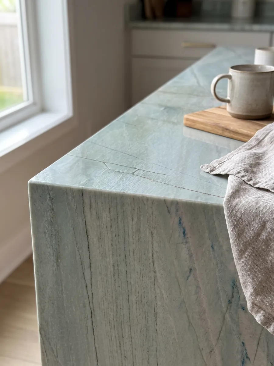 Canto recto de una cubierta de cocina en cuarcita verde Emerald Green con la veta continuando por el borde: verde agua claro con finas líneas oscuras verticales y pequeños destellos azules