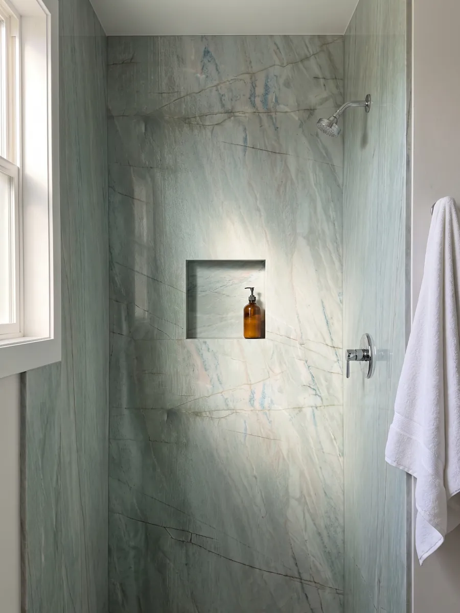 Ducha revestida con placas enteras de cuarcita verde Emerald Green con nicho empotrado: verde agua claro con finas líneas oscuras verticales y pequeños destellos azules