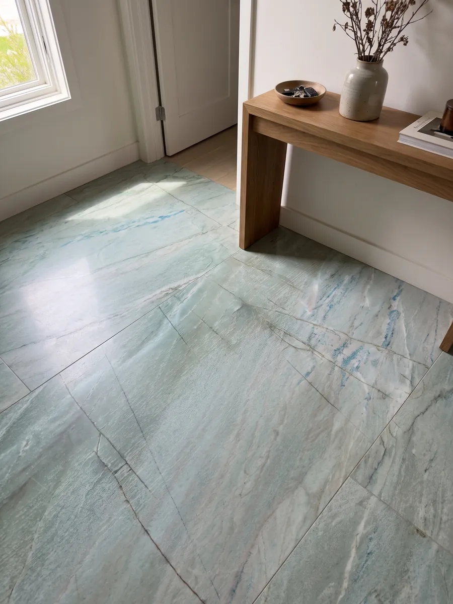 Piso de recibidor en placas grandes de cuarcita verde Emerald Green con luz natural: verde agua claro con finas líneas oscuras verticales y pequeños destellos azules