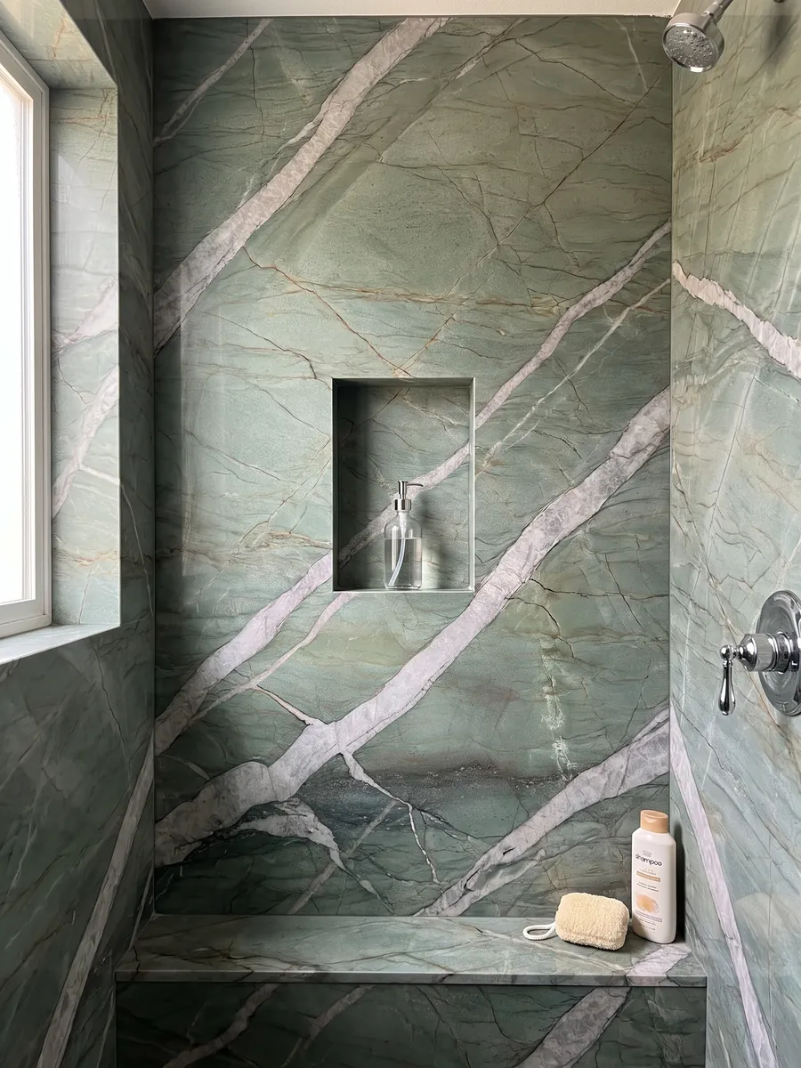 Ducha revestida con placas enteras de cuarcita verde Patagonia Green con nicho empotrado: verde jade atravesado por vetas anchas gris claro en diagonal