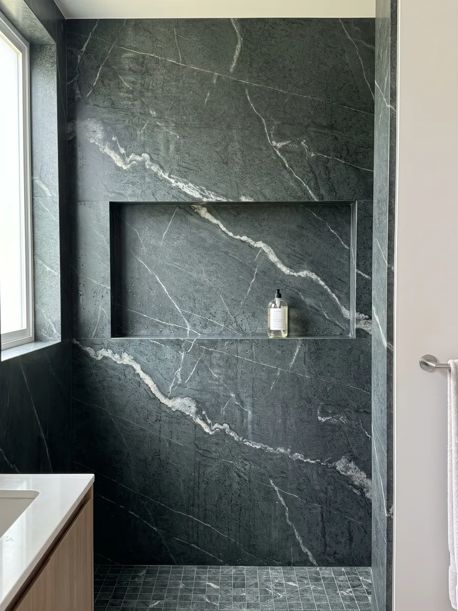 Ducha revestida con placas enteras de cuarcita verde Pietra Ollare con nicho empotrado: verde casi negro granulado con una veta blanca serpenteante