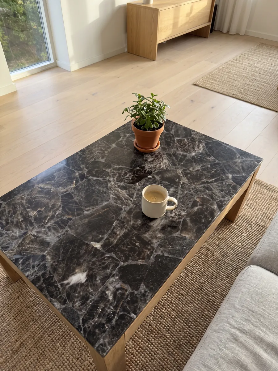 Mesa de centro con cubierta de Cuarzo Ahumado en una sala: fragmentos gris oscuro casi negro delimitados por bordes y líneas claras