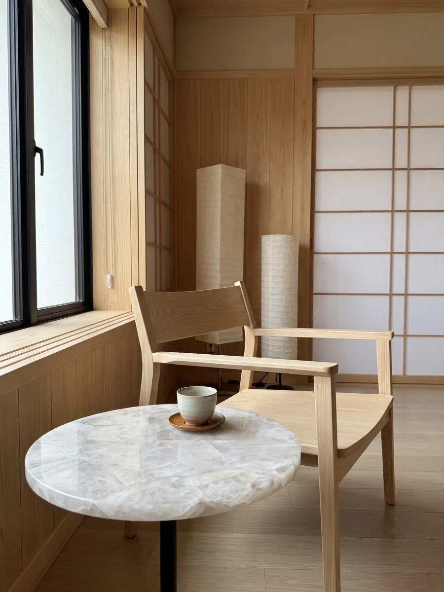 Mesa auxiliar con cubierta de Cuarzo Blanco junto a un sillón: blanco grisáceo cristalino y suave, con fragmentos apenas marcados