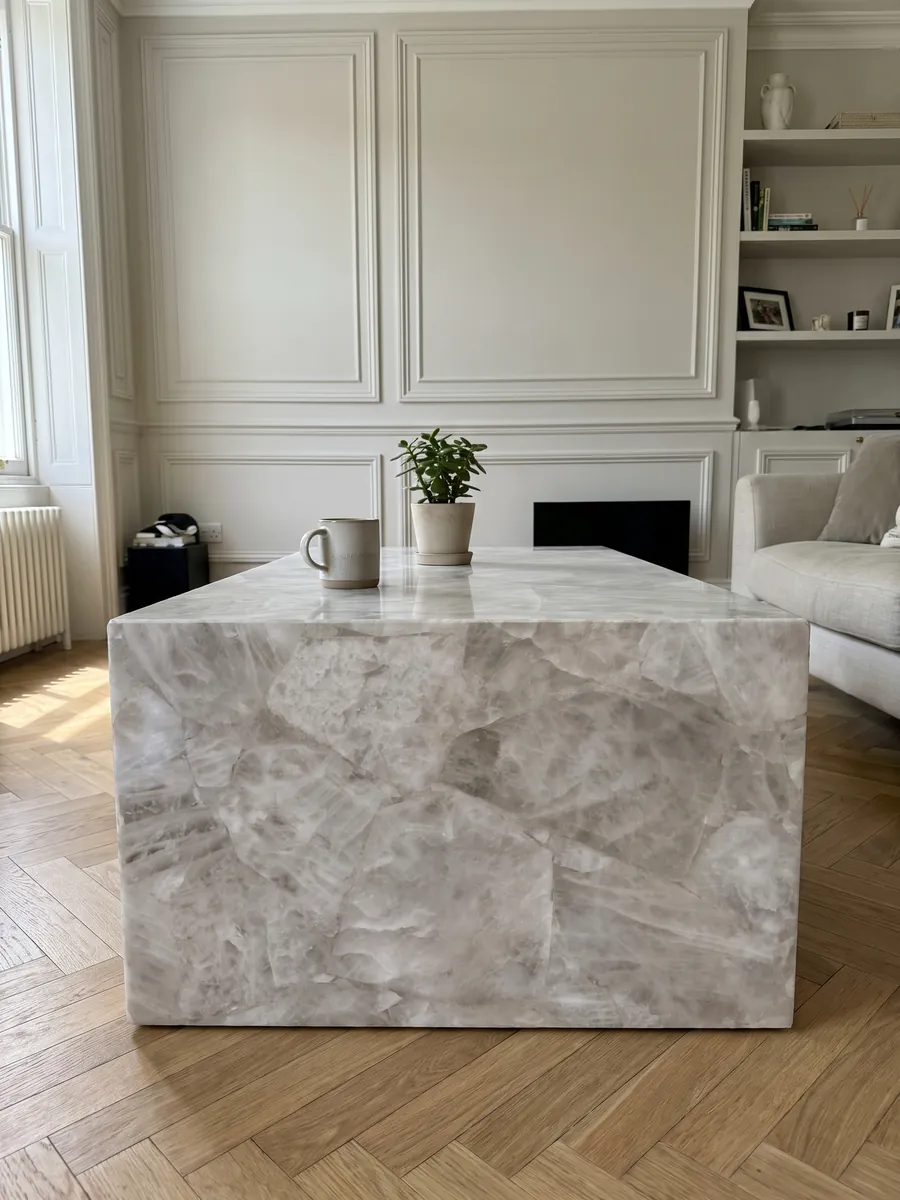 Mesa de centro con cubierta de Cuarzo Blanco en una sala: blanco grisáceo cristalino y suave, con fragmentos apenas marcados