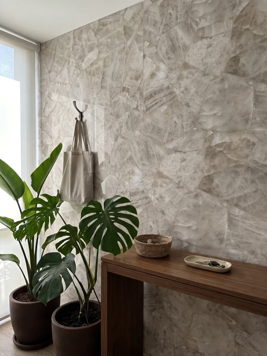 Pared de recibidor revestida con Cuarzo Blanco con consola estrecha: blanco grisáceo cristalino y suave, con fragmentos apenas marcados