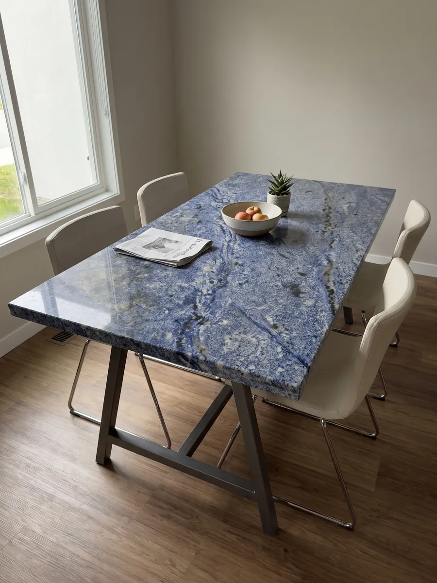 Mesa de comedor con cubierta de Granito Azul Bahia sobre base de acero: azul intenso granulado con zonas blancas y manchas oscuras