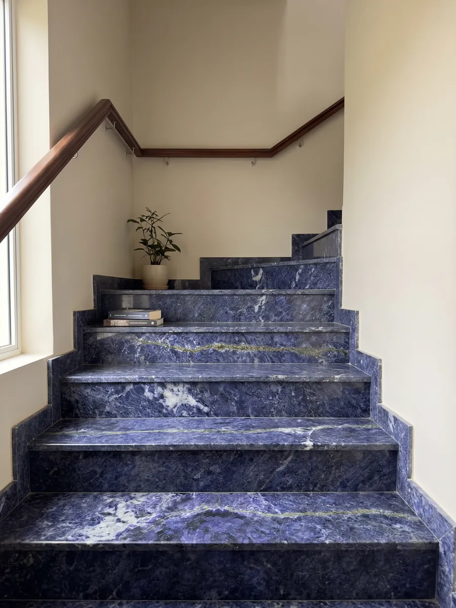 Escalera interior con peldaños de granito azul Jeriba Blue con pasamanos: azul violeta intenso con nubes blancas y una línea verde dorada