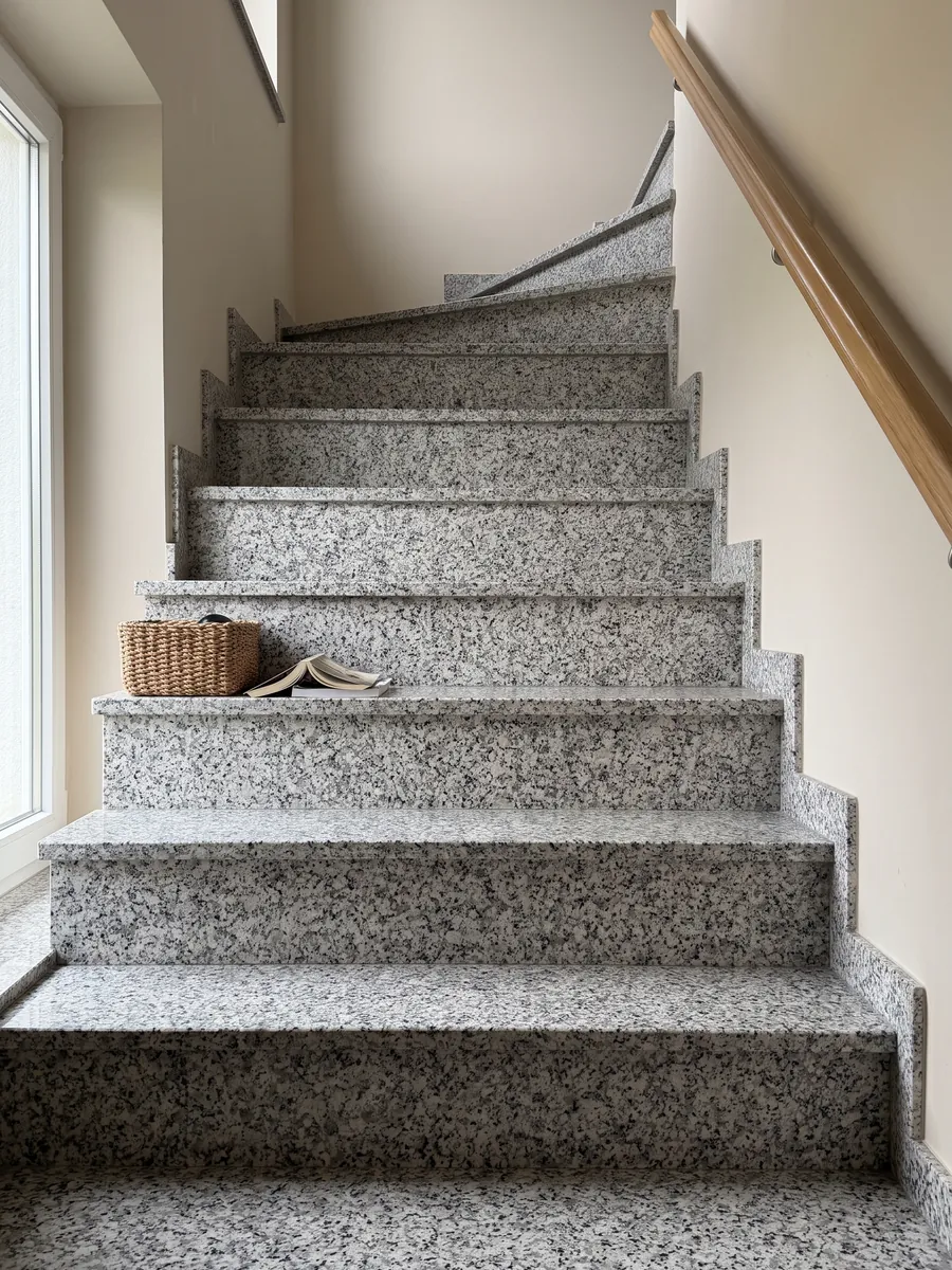 Escalera interior con peldaños de granito blanco Sardo Bianco con pasamanos: blanco de grano grueso con cristales grises y negros