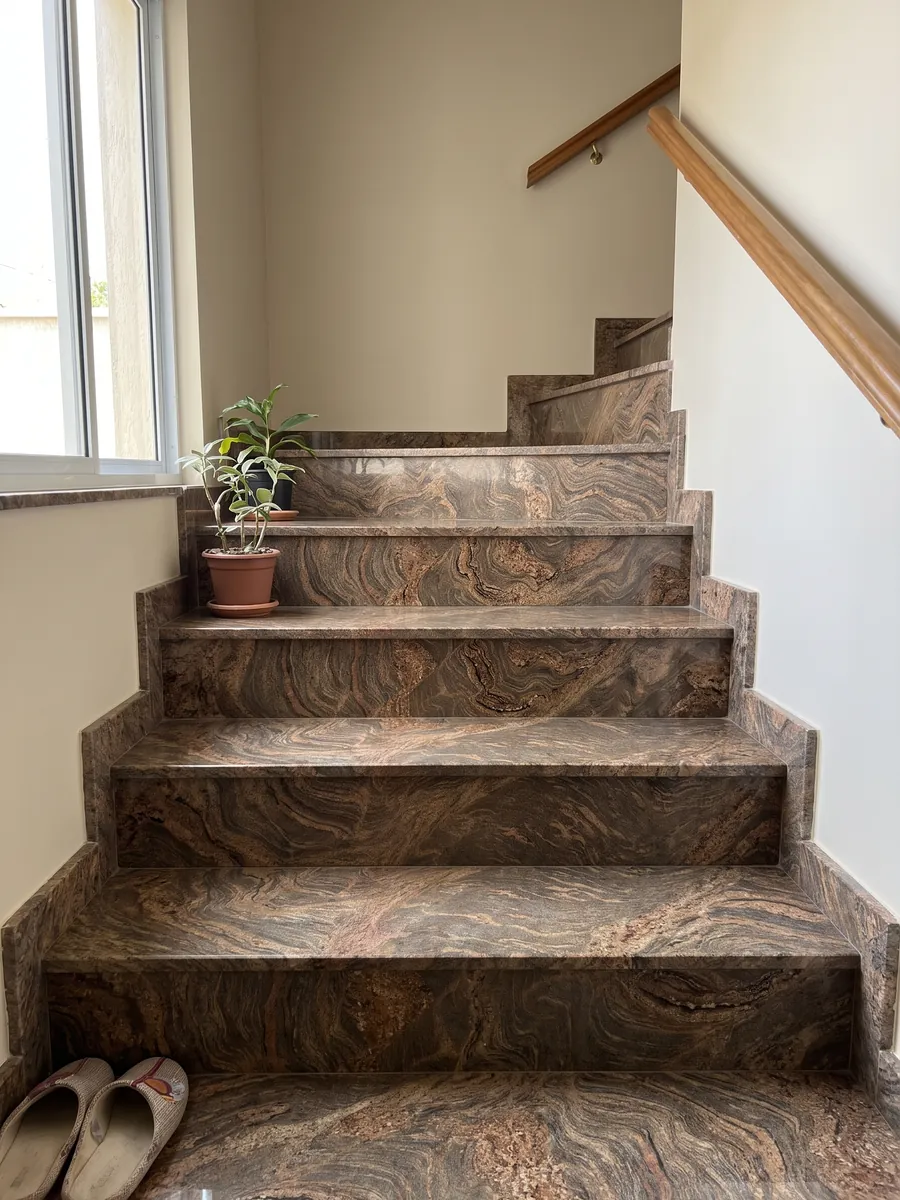 Escalera interior con peldaños de granito café Juparana Dourado con pasamanos: marrón ocre con ondas y remolinos rojizos muy movidos