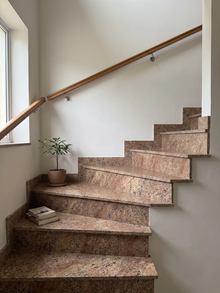 Escalera interior con peldaños de granito café Juparana Florence con pasamanos: marrón cobrizo granulado con zonas beige difusas