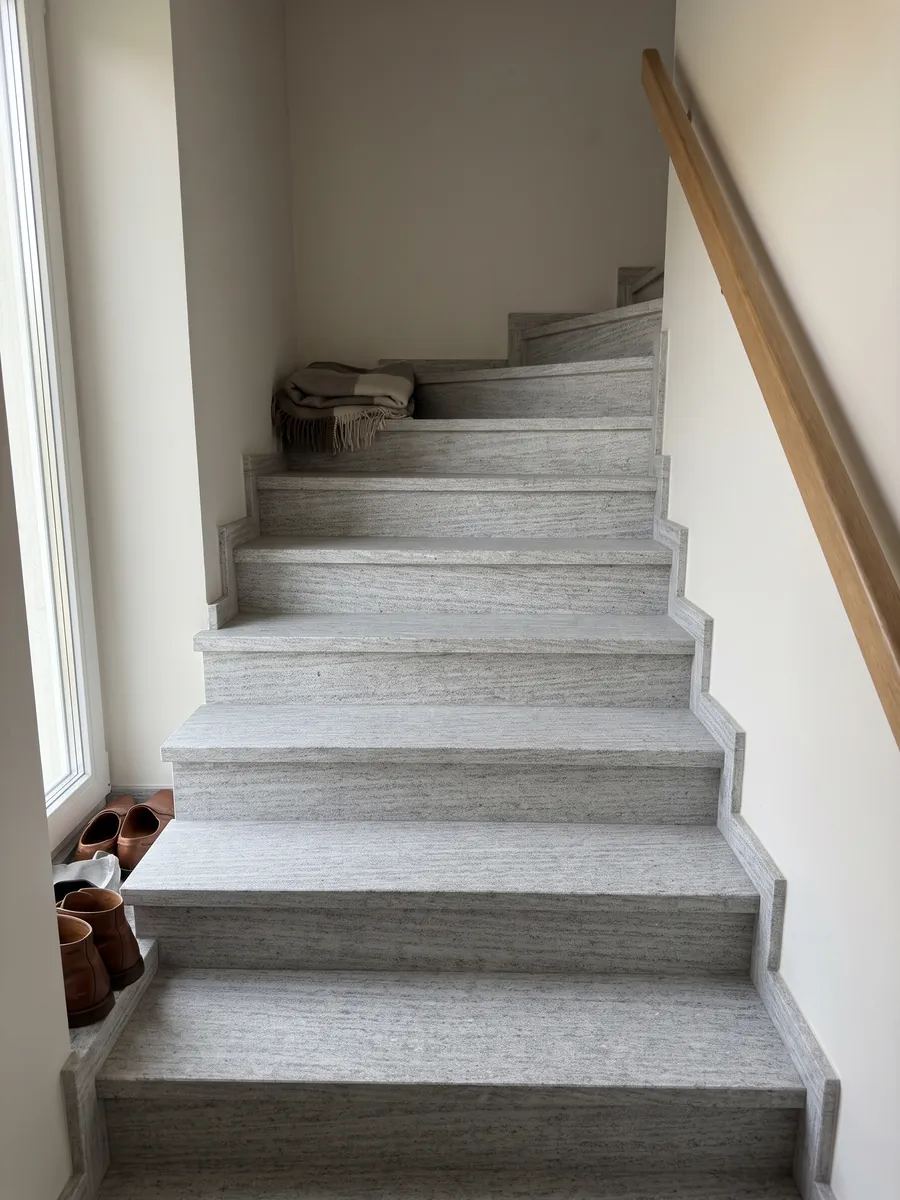 Escalera interior con peldaños de granito gris Beola Bianca con pasamanos: gris claro con rayado horizontal fino y pequeños brillos