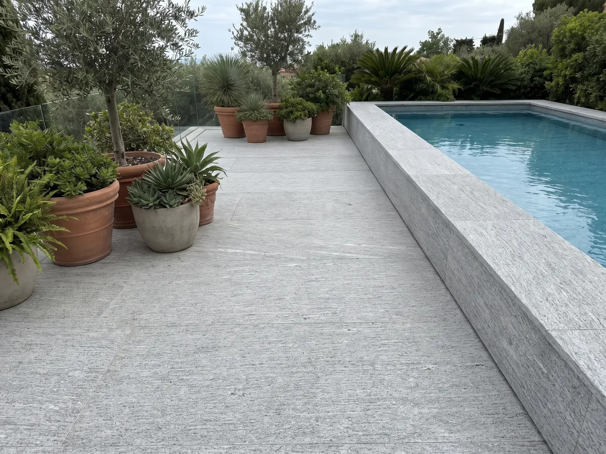 Piso de terraza y borde de piscina en granito gris Beola Bianca con macetas: gris claro con rayado horizontal fino y pequeños brillos