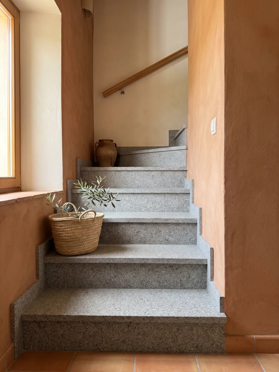 Escalera interior con peldaños de Granito Gris Mara con pasamanos: gris neutro con grano fino blanco y negro repartido de forma pareja