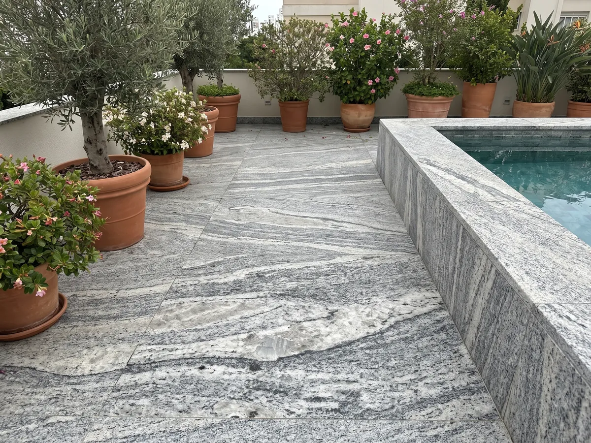 Piso de terraza y borde de piscina en granito gris Piracema White con macetas: bandas onduladas gris y blanco con un gran fragmento claro