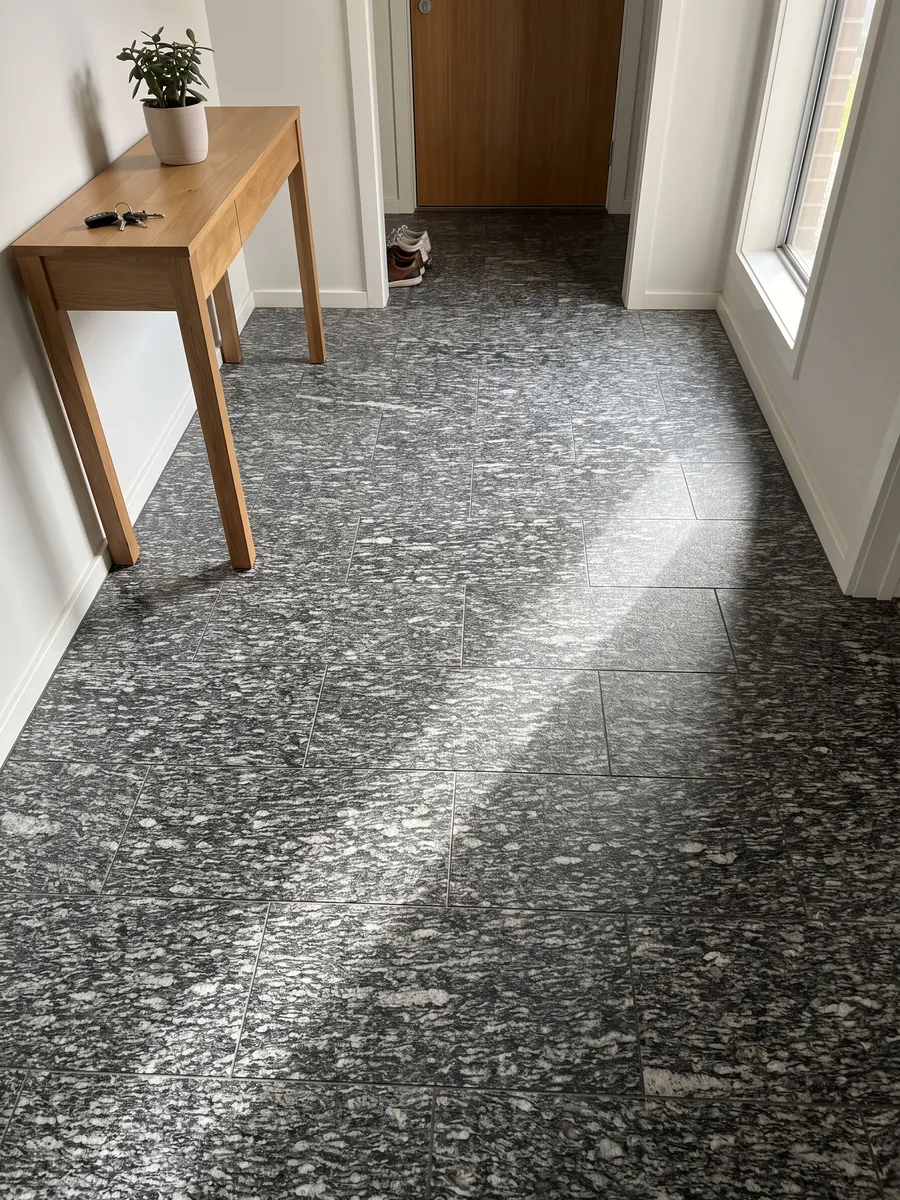 Piso de recibidor en placas grandes de granito gris Serizzo con luz natural: gris oscuro con trazos blancos alargados horizontales