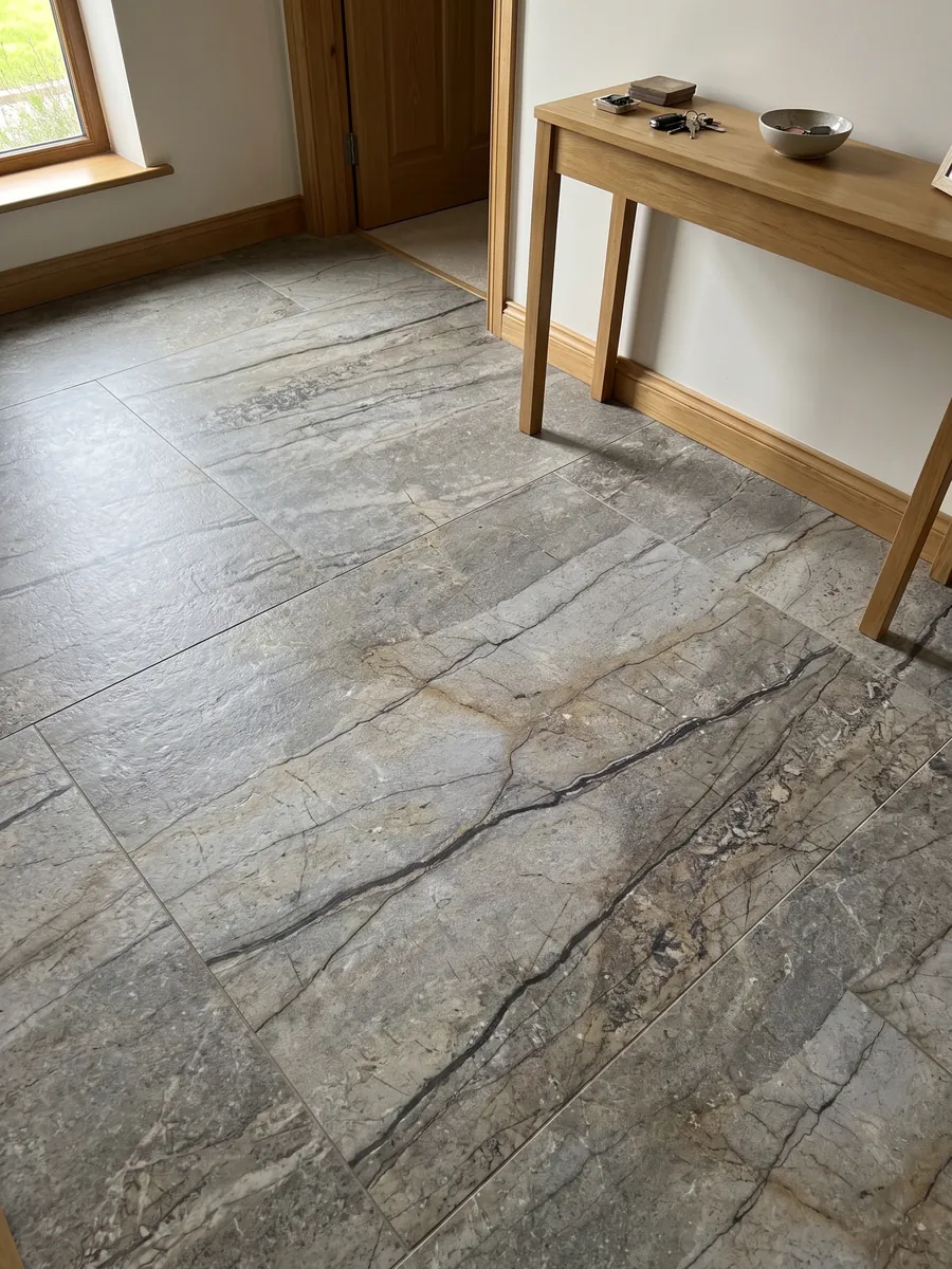 Piso de recibidor en placas grandes de granito gris Silver Roots con luz natural: gris topo con vetas oscuras horizontales y aspecto de piedra natural