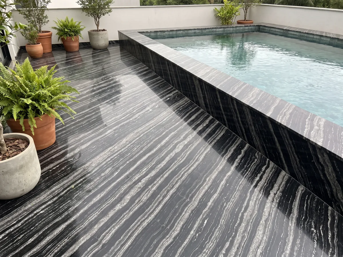 Piso de terraza y borde de piscina en granito negro Agata Black con macetas: negro con bandas onduladas gris plata paralelas en diagonal