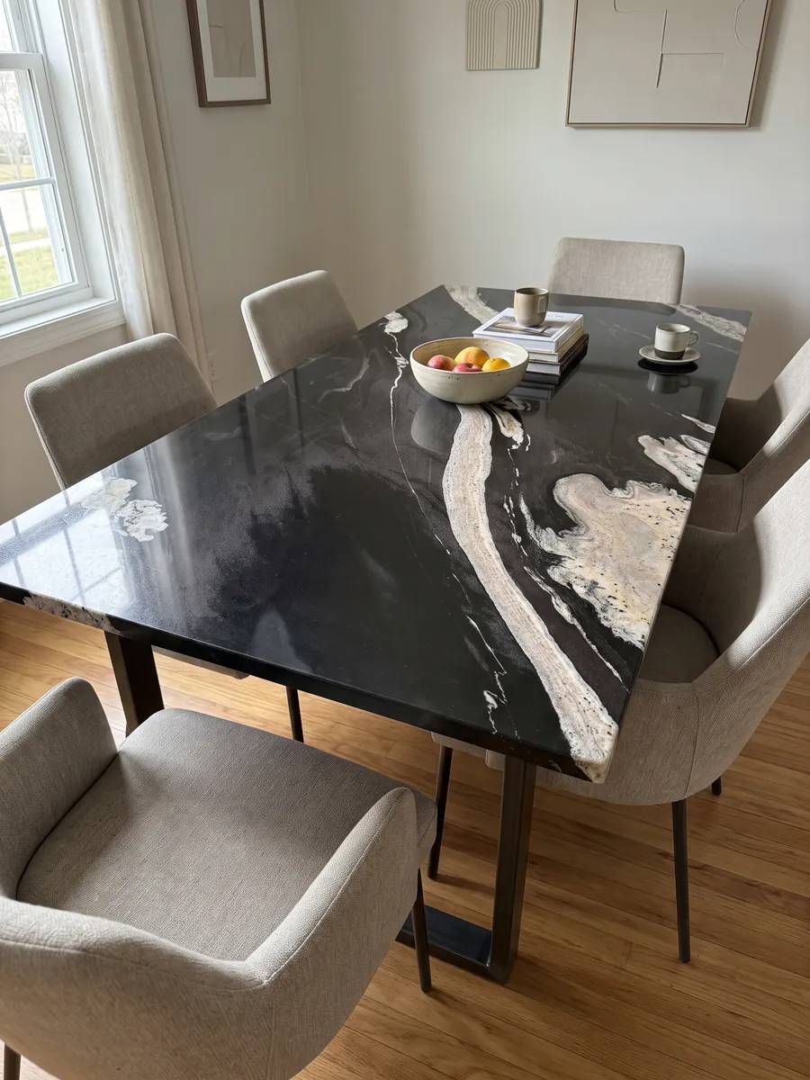 Mesa de comedor con cubierta de granito negro Copacabana sobre base de acero: negro con una banda crema ondulada que cruza en diagonal