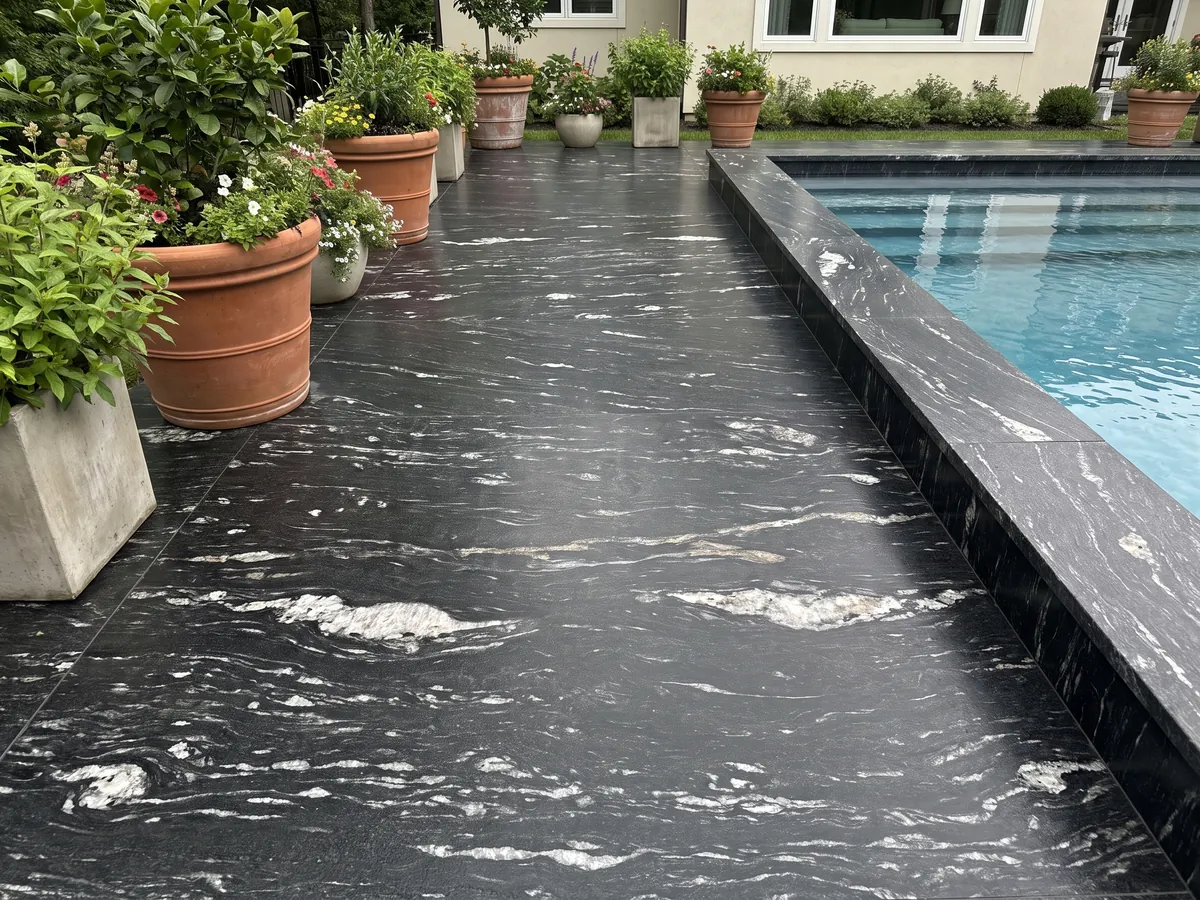 Piso de terraza y borde de piscina en granito negro Cosmic Black con macetas: negro con trazos blancos ondulados horizontales