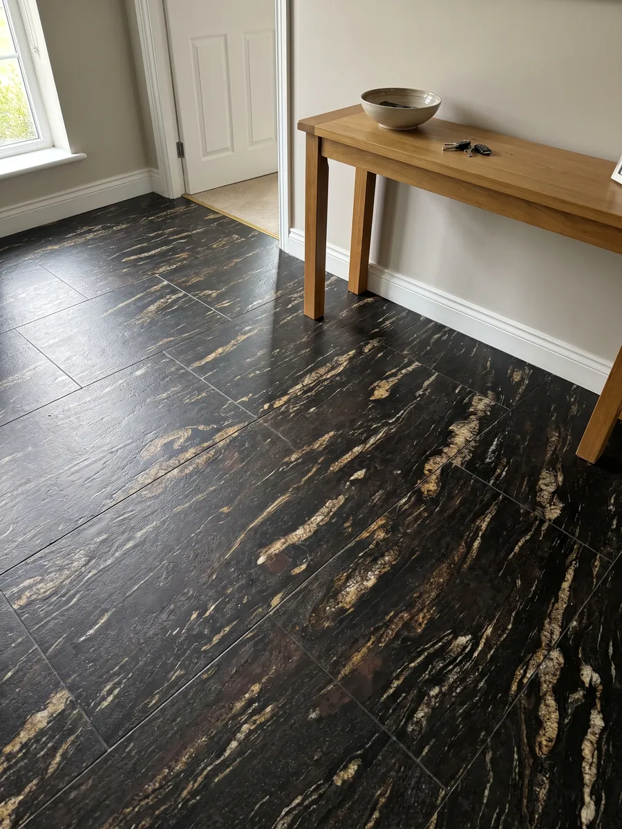 Piso de recibidor en placas grandes de granito negro Matrix con luz natural: negro con trazos dorados alargados en diagonal