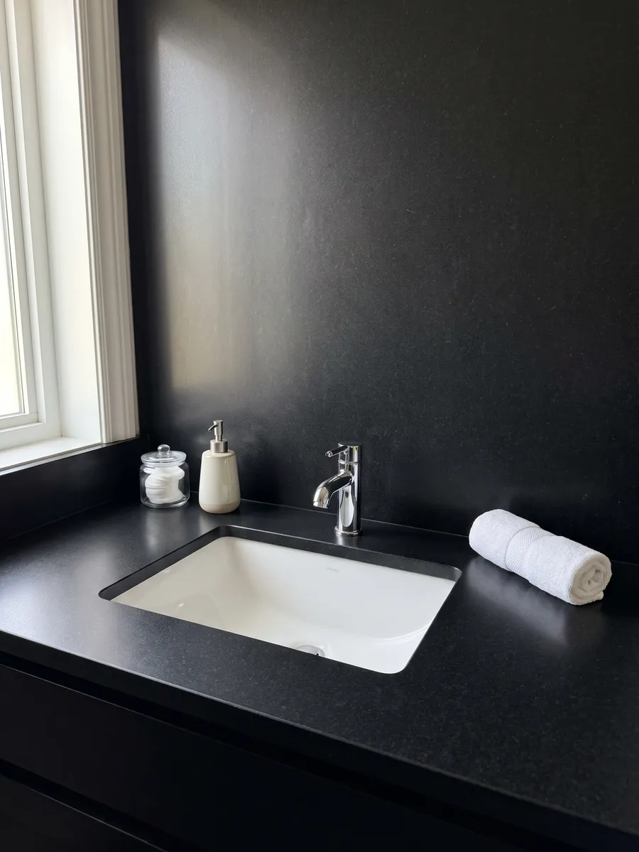 Cubierta de lavabo y pared de baño en granito negro Nero Assoluto con lavamanos blanco y grifería cromada: negro uniforme sin dibujo