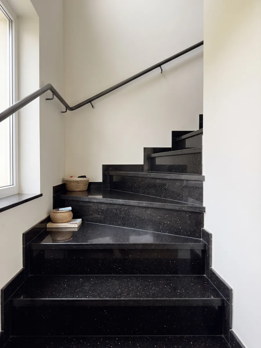 Escalera interior con peldaños de granito negro Star Galaxy con pasamanos: negro con pequeños puntos dorados que brillan