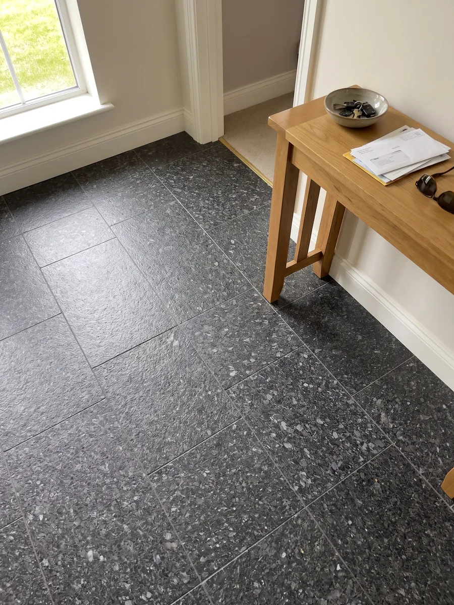 Piso de recibidor en placas grandes de granito negro Stargate con luz natural: gris antracita granulado con cristales grises y violáceos