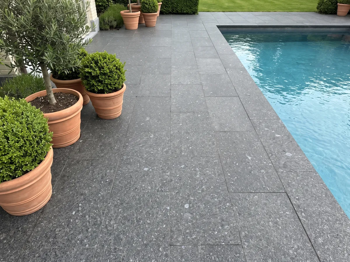 Piso de terraza y borde de piscina en granito negro Stargate con macetas: gris antracita granulado con cristales grises y violáceos