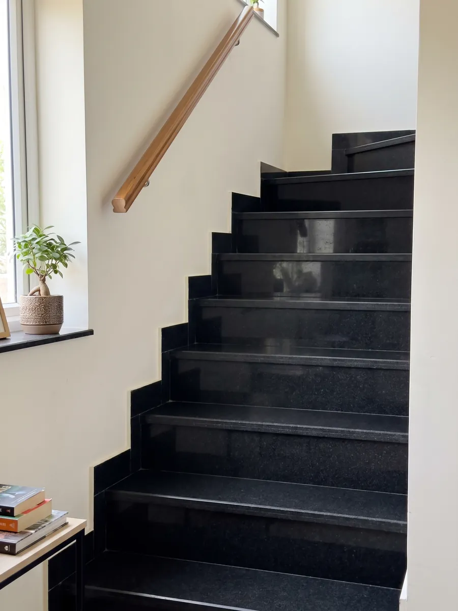 Escalera interior con peldaños de granito negro Titanium Black con pasamanos: negro casi liso y homogéneo, con un grano finísimo que solo se nota de cerca