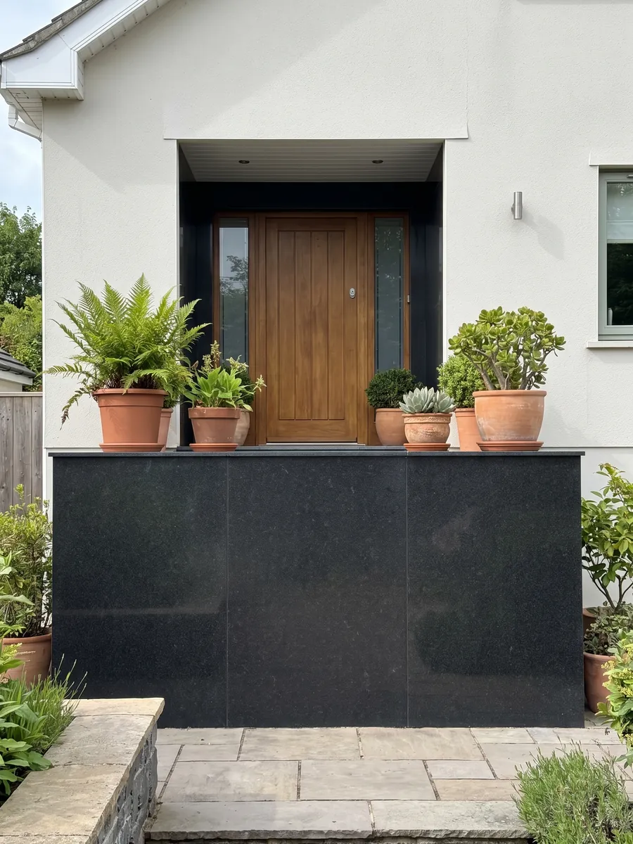 Fachada de casa revestida con granito negro Titanium Black junto a una puerta de madera: negro casi liso y homogéneo, con un grano finísimo que solo se nota de cerca