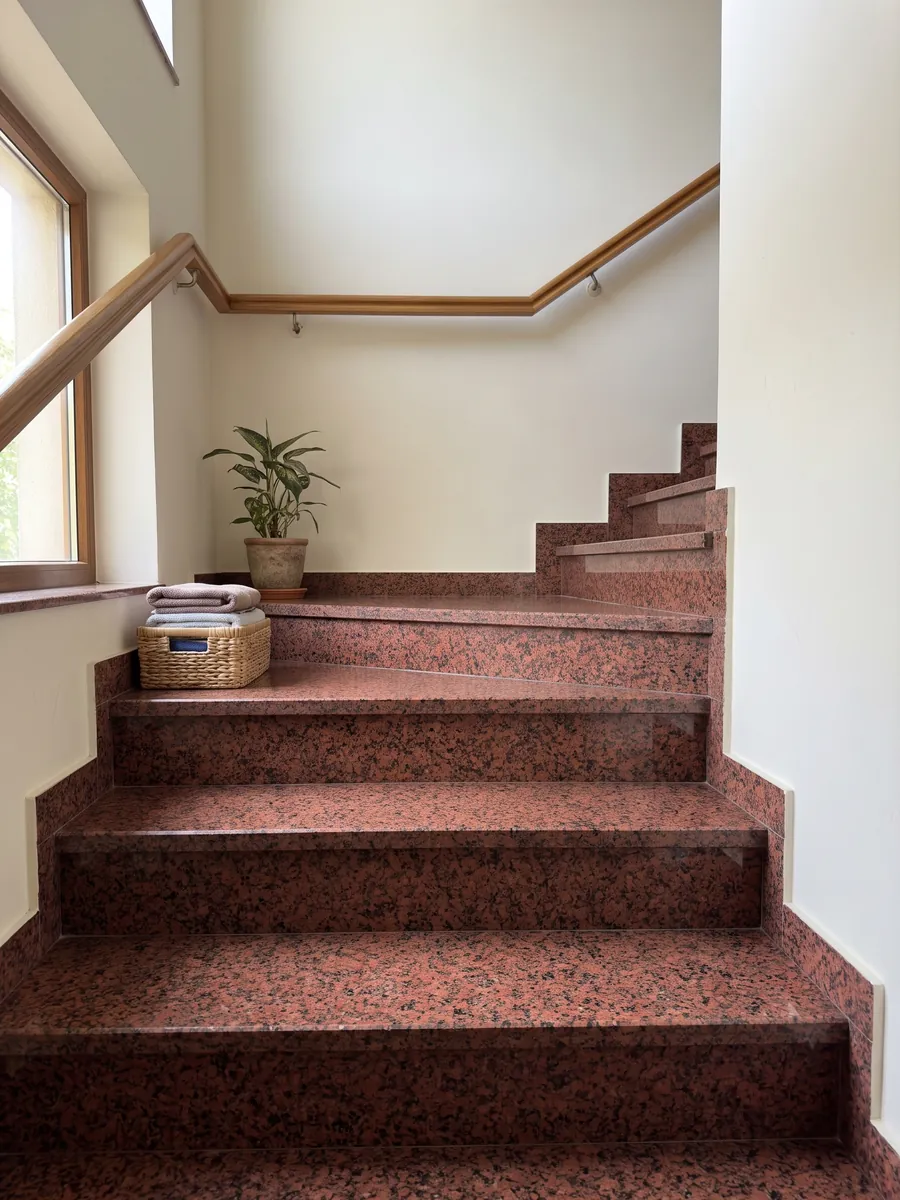 Escalera interior con peldaños de granito rojo Balmoral Red con pasamanos: rojo intenso granulado con puntos negros repartidos