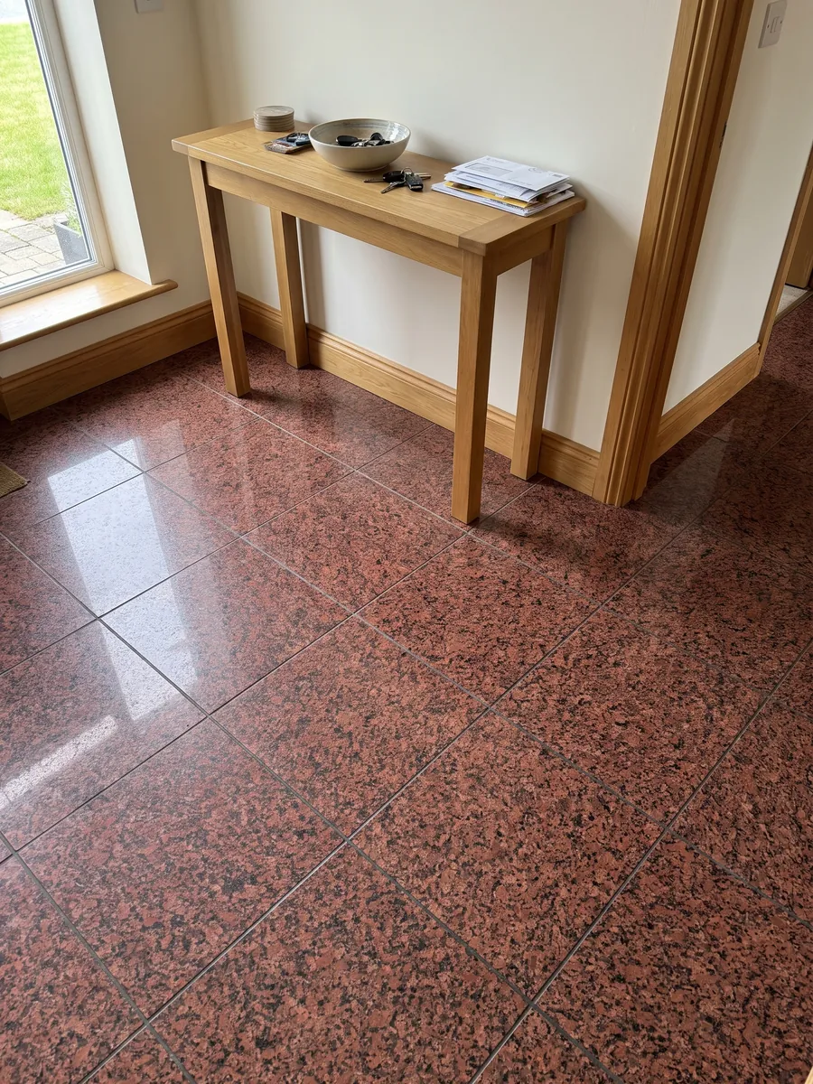 Piso de recibidor en placas grandes de granito rojo Balmoral Red con luz natural: rojo intenso granulado con puntos negros repartidos