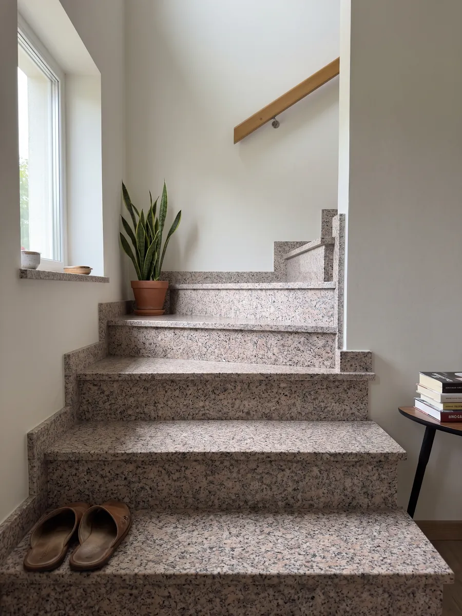 Escalera interior con peldaños de Granito Rosa Beta con pasamanos: grano blanco con puntos rosa pálido y negros