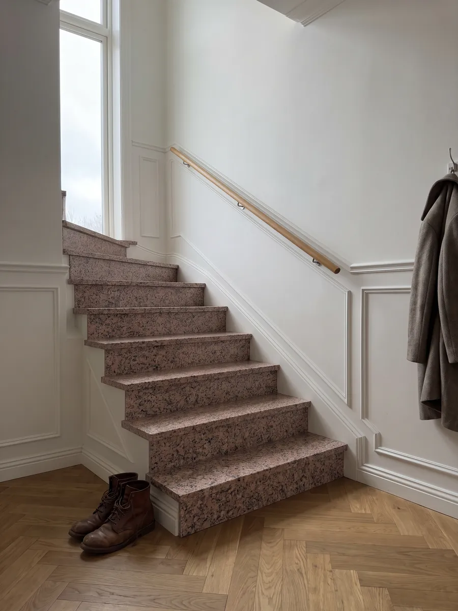 Escalera interior con peldaños de Granito Rosa de Salto con pasamanos: rosado moteado con puntos gris oscuro y blancos